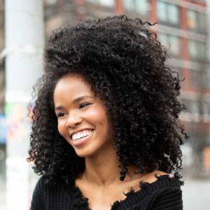 Woman with curly hair standing outside laughing